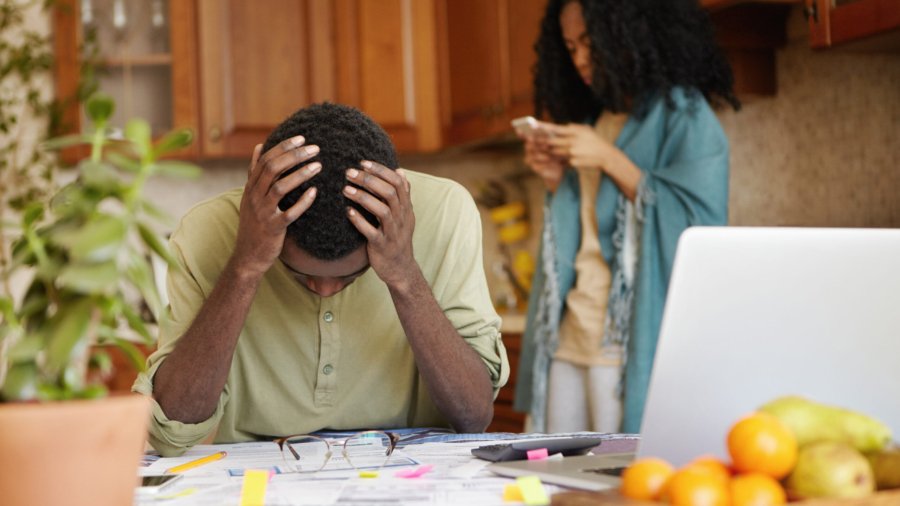 Desperate dark-skinned male touching head with both hands, feeling absolutely devastated, can't stand financial pressure, not able to pay gas and electricity bills anymore because of many debts