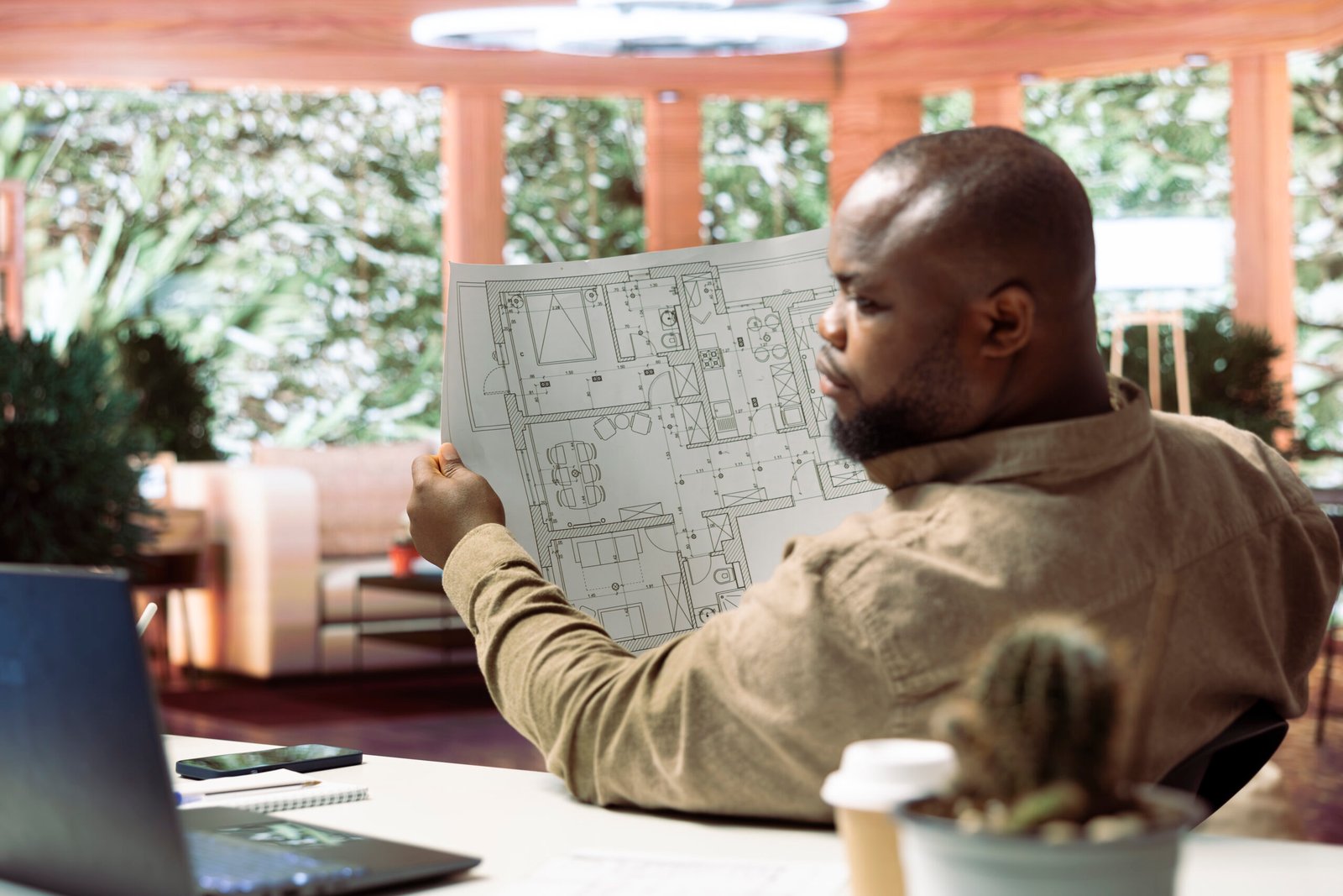 Small business owner analyzing architectural sketches and planning office spaces, focusing on blueprint review and strategic layout design. Evaluating property for modern and professional workspace.