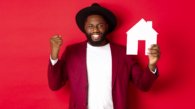 Real estate. Cheerful Black man rejoicing and showing paper home maket, standing over red background.