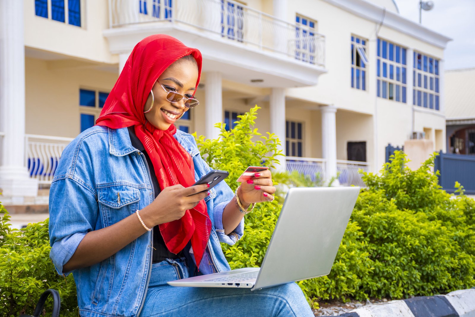 A beautiful young African woman smiling while using her laptop outside